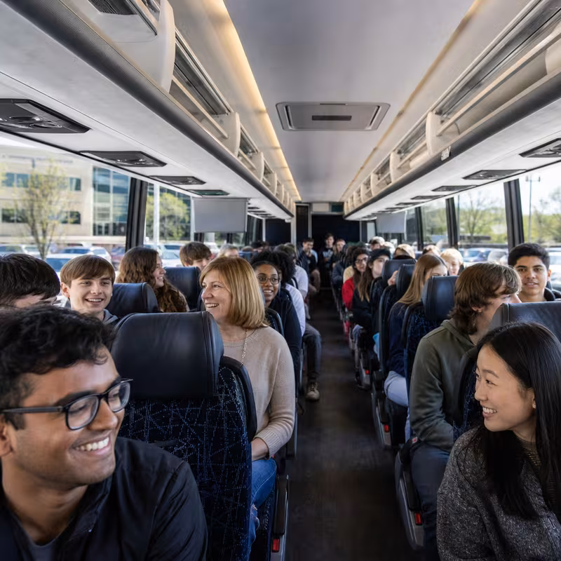Group boarding a white charter bus for School Transportation transportation in Seattle